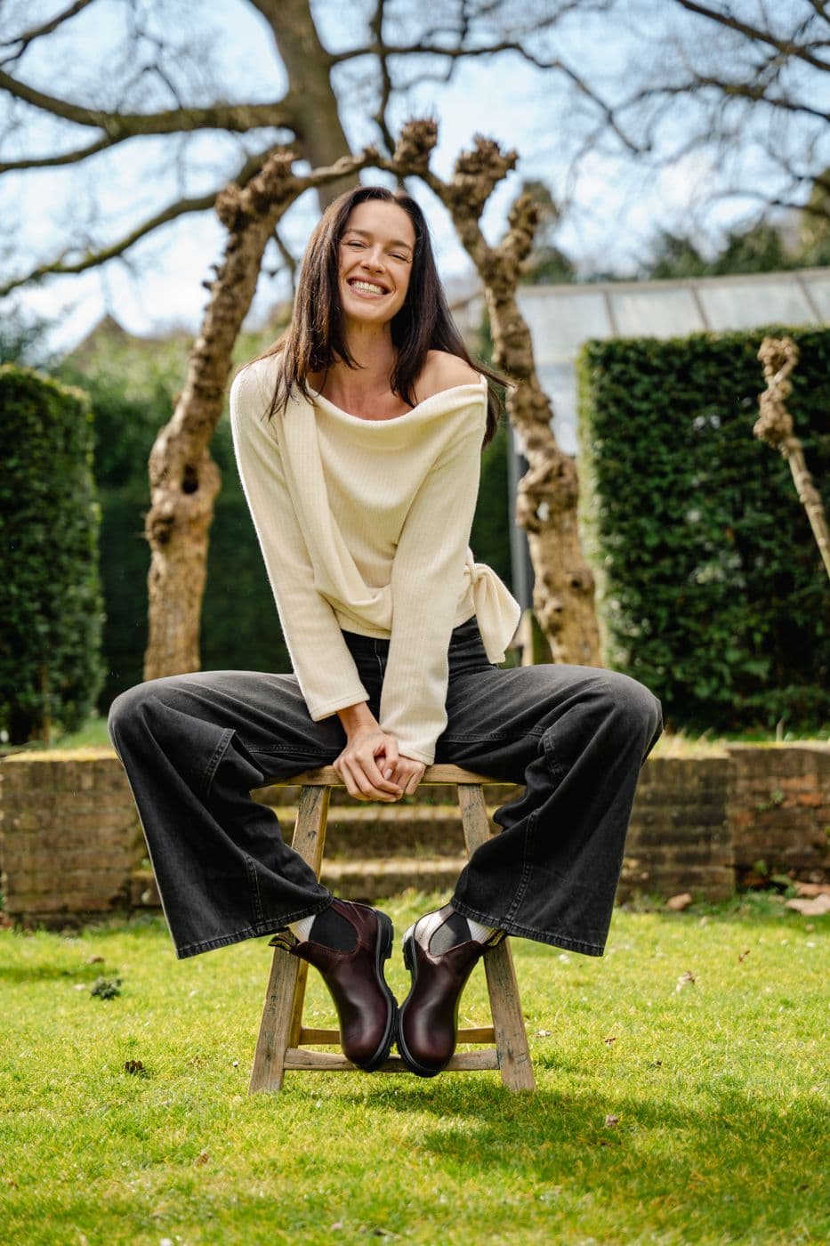 Model in crème knit op een krukje in de tuin