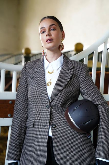 Model in tweed blazer met helm onder de arm